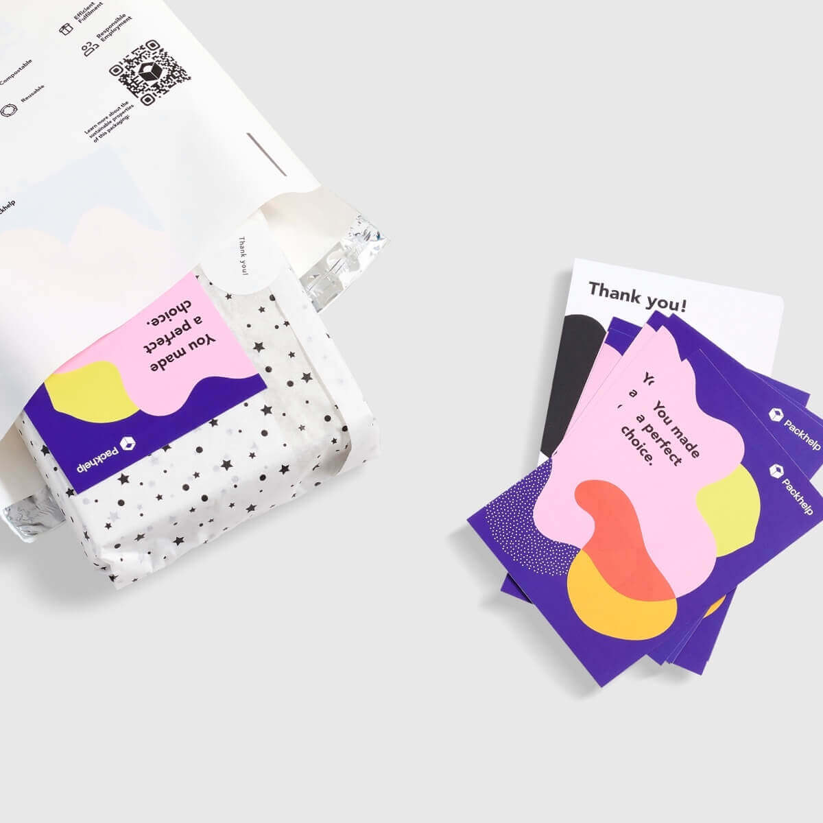 Tarjetas de agradecimiento personalizadas junto a una bolsa y una caja postal